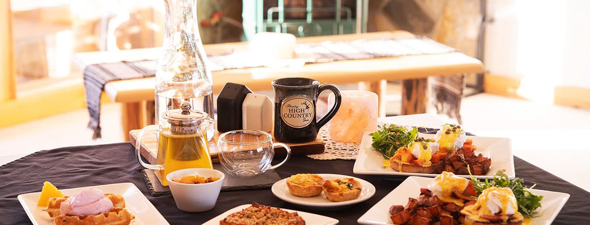 A beautifully arranged breakfast table featuring various dishes, beverages, and garnishes.