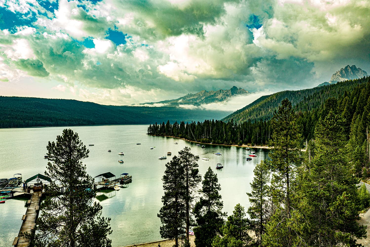 A tranquil lake surrounded by dense forests and mountains under a dramatic sky. A tranquil lake surrounded by dense forests and mountains under a dramatic sky.