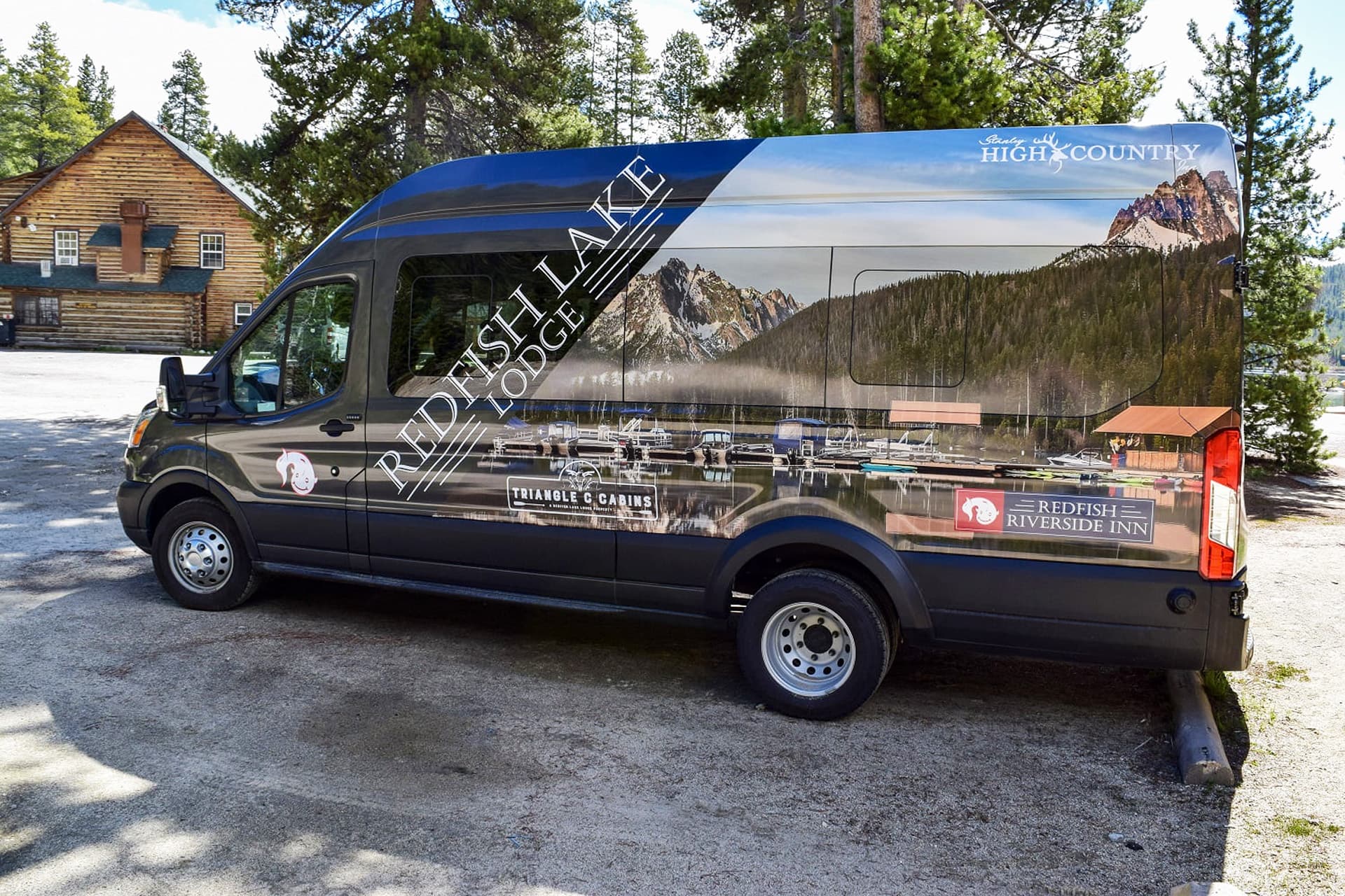 A van featuring an advertisement for Redfish Lake Lodge parked in a scenic outdoor area.