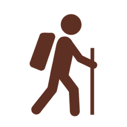 A hiker with a backpack walking with a staff.