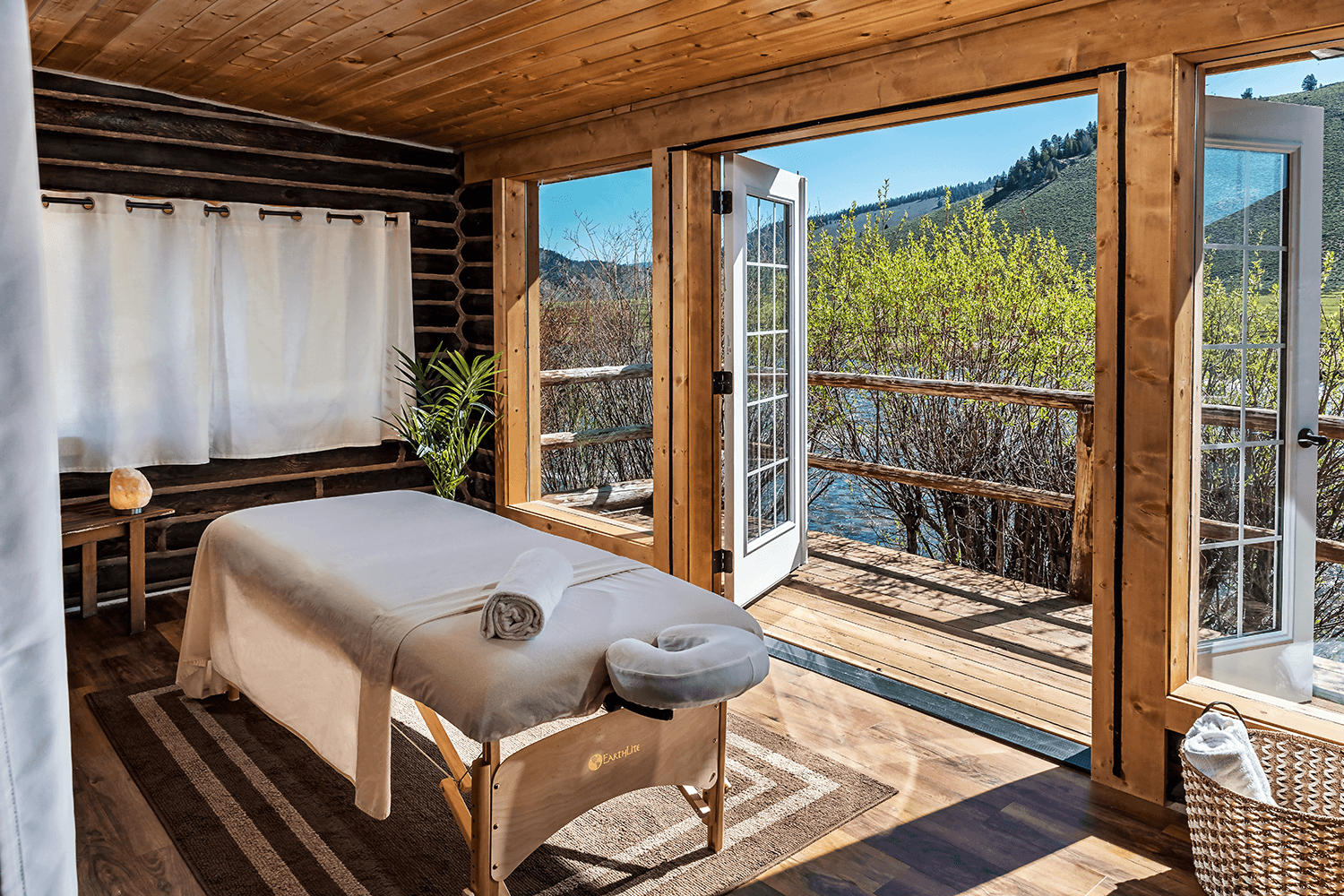 A serene massage room with a view of nature through open doors.