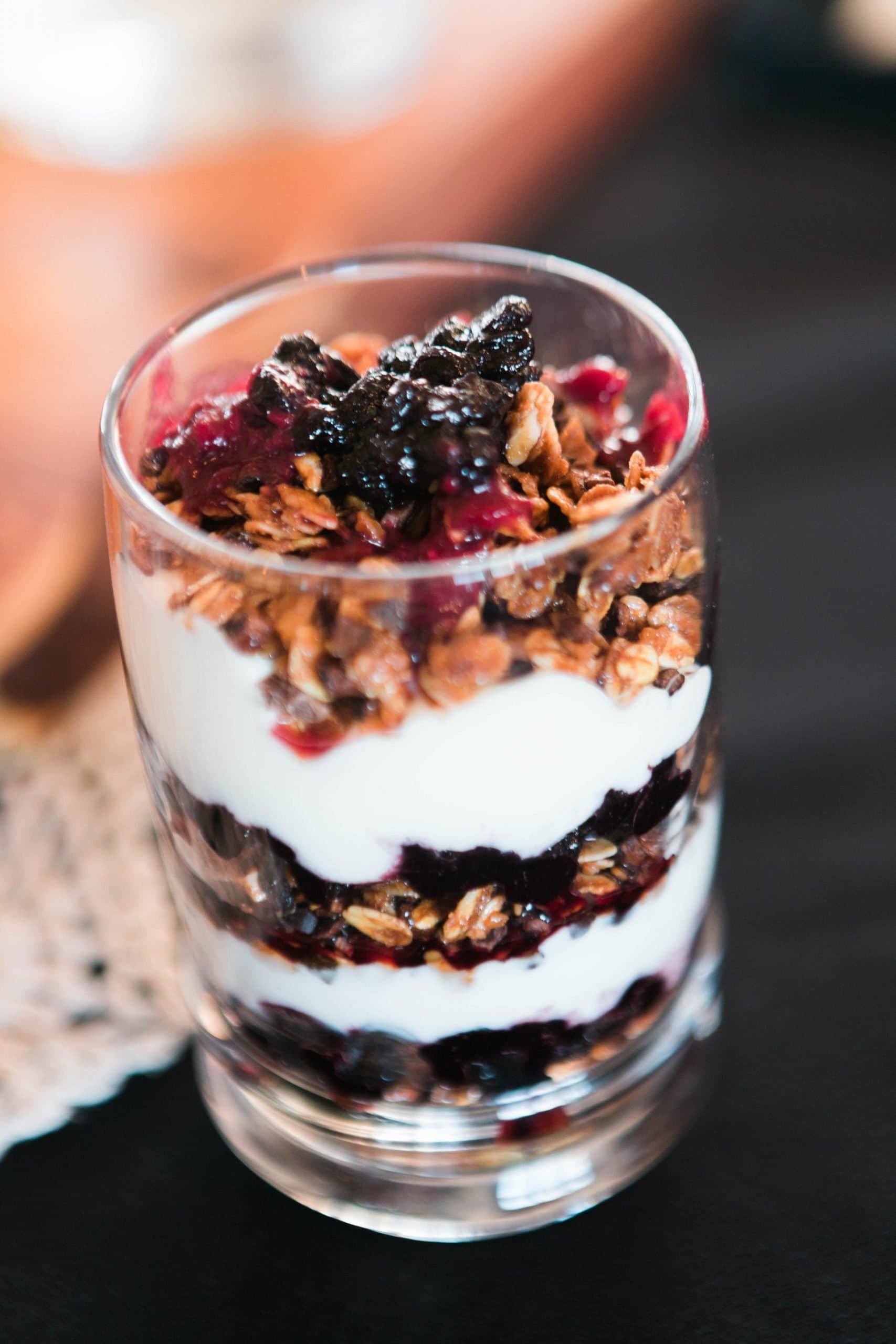 A glass parfait layered with yogurt, granola, and berry compote.