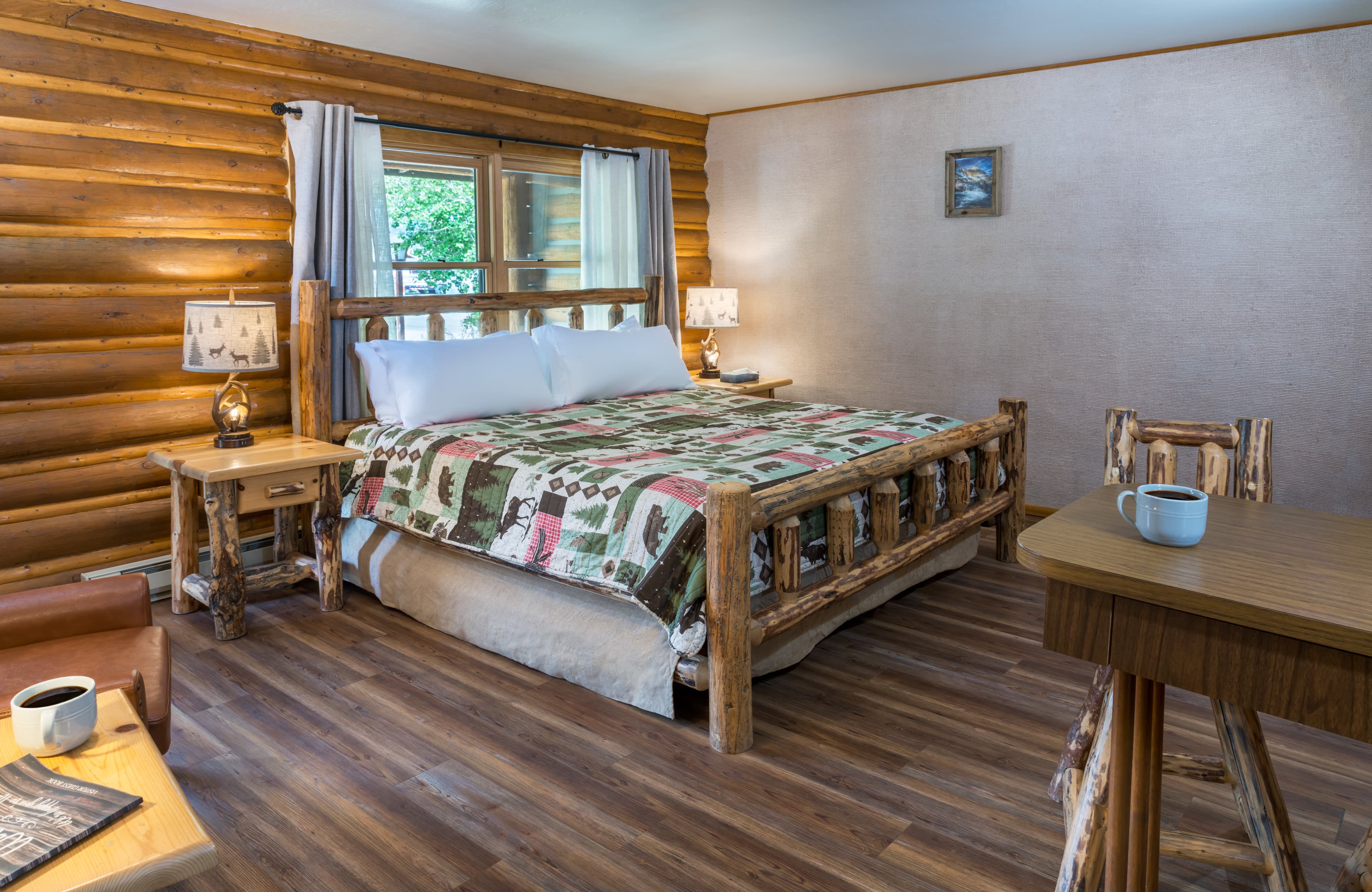 A cozy cabin interior featuring a log-style bed with a patterned quilt and wooden furniture.