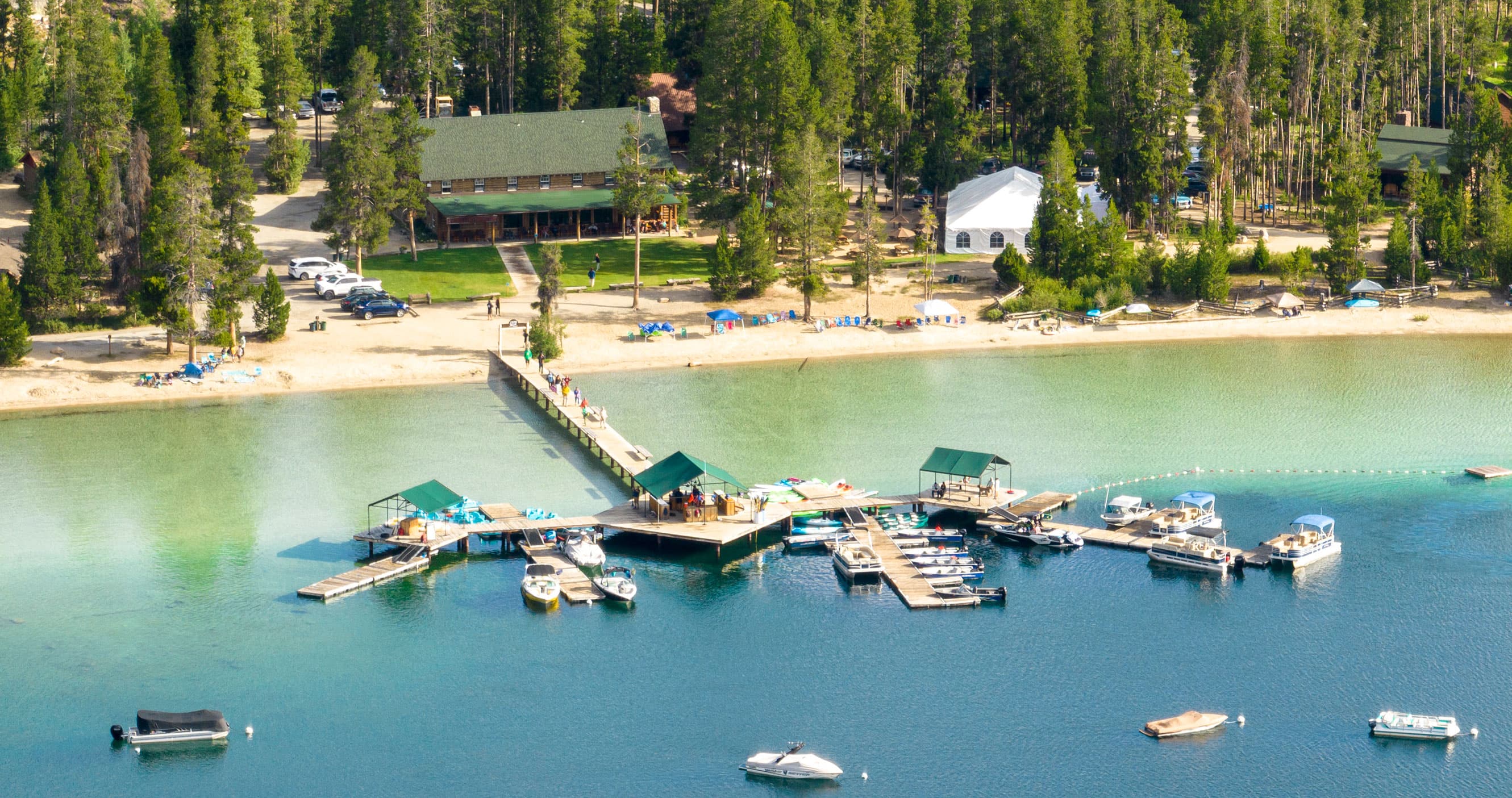 Aerial view of a lakeside dock with boats, surrounded by trees and buildings.