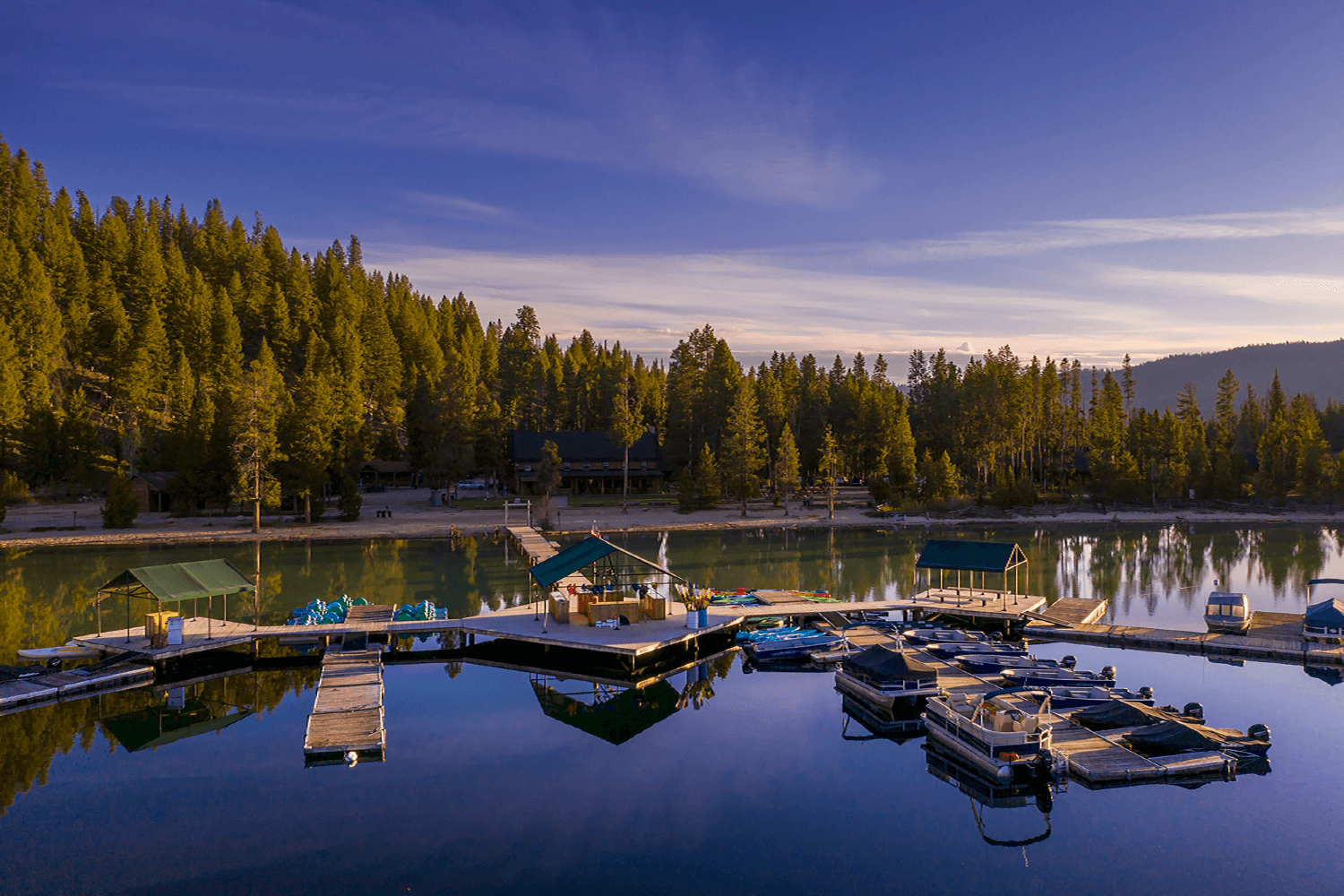 A tranquil lake surrounded by evergreen trees, featuring docks and boats reflecting in the calm water. A tranquil lake surrounded by evergreen trees, featuring docks and boats reflecting in the calm water.