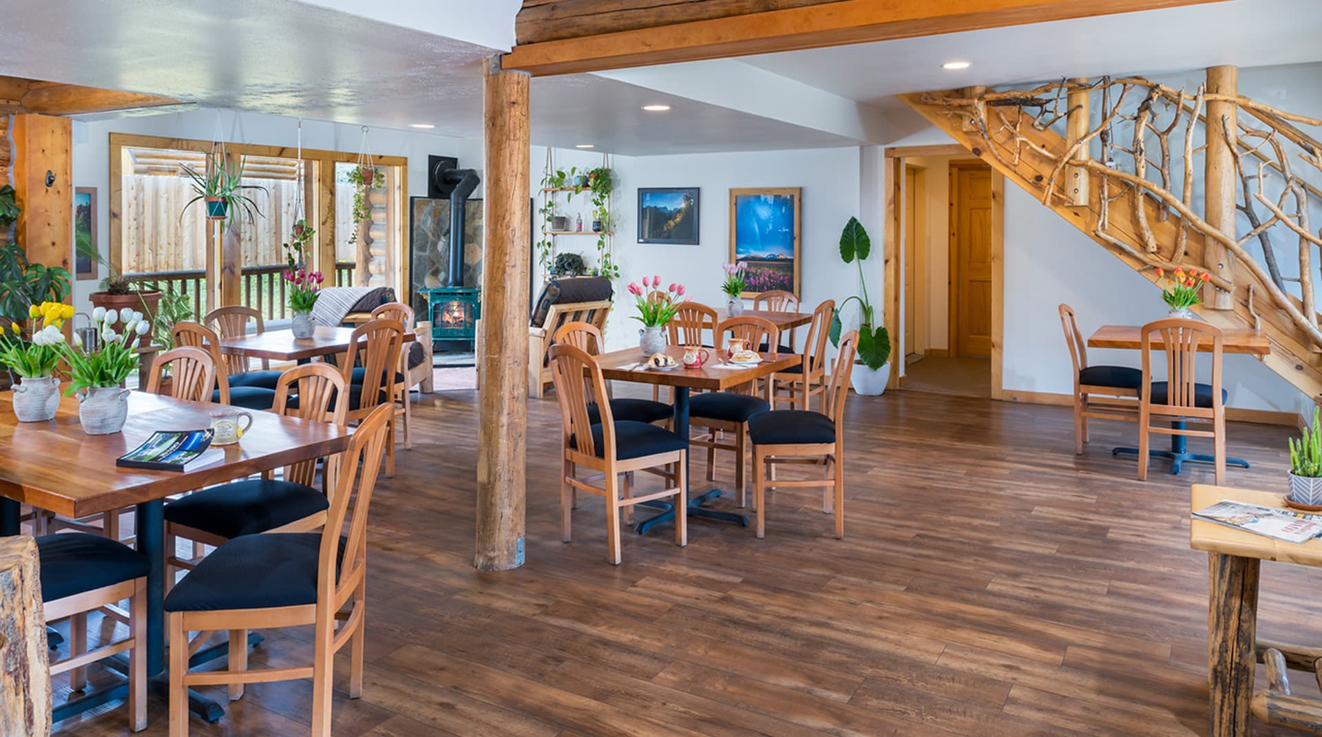 Bright, inviting dining area with wooden tables, chairs, and a staircase. Bright, inviting dining area with wooden tables, chairs, and a staircase.