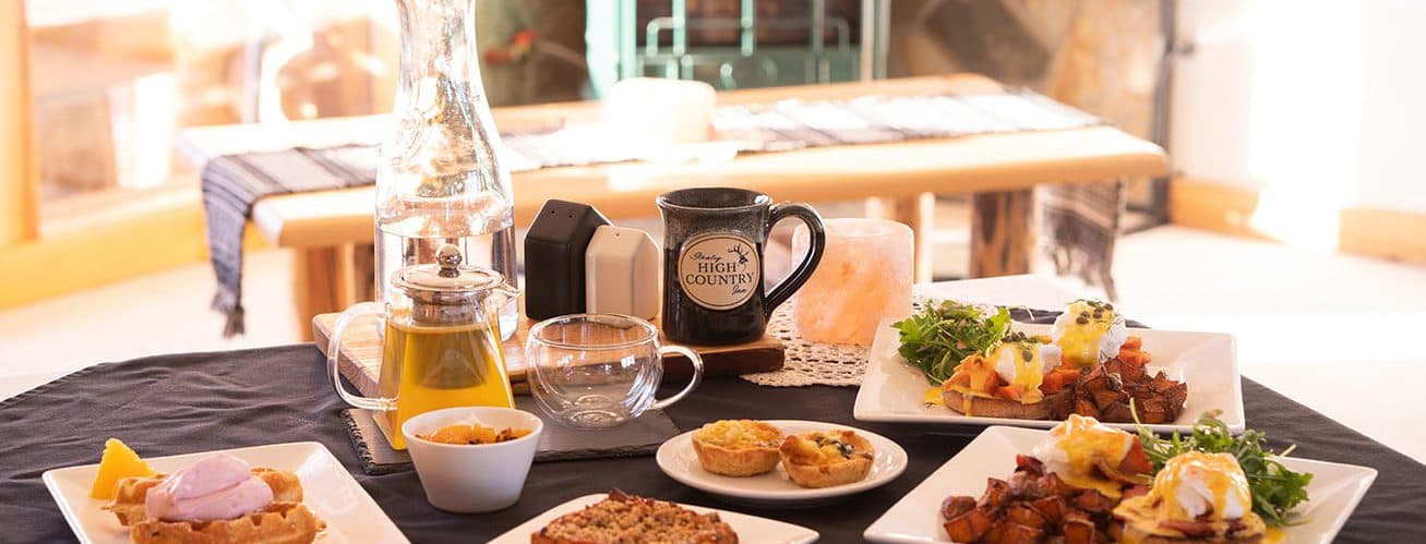 A beautifully arranged breakfast spread featuring waffles, eggs Benedict, bacon, and beverages on a table. A beautifully arranged breakfast spread featuring waffles, eggs Benedict, bacon, and beverages on a table.