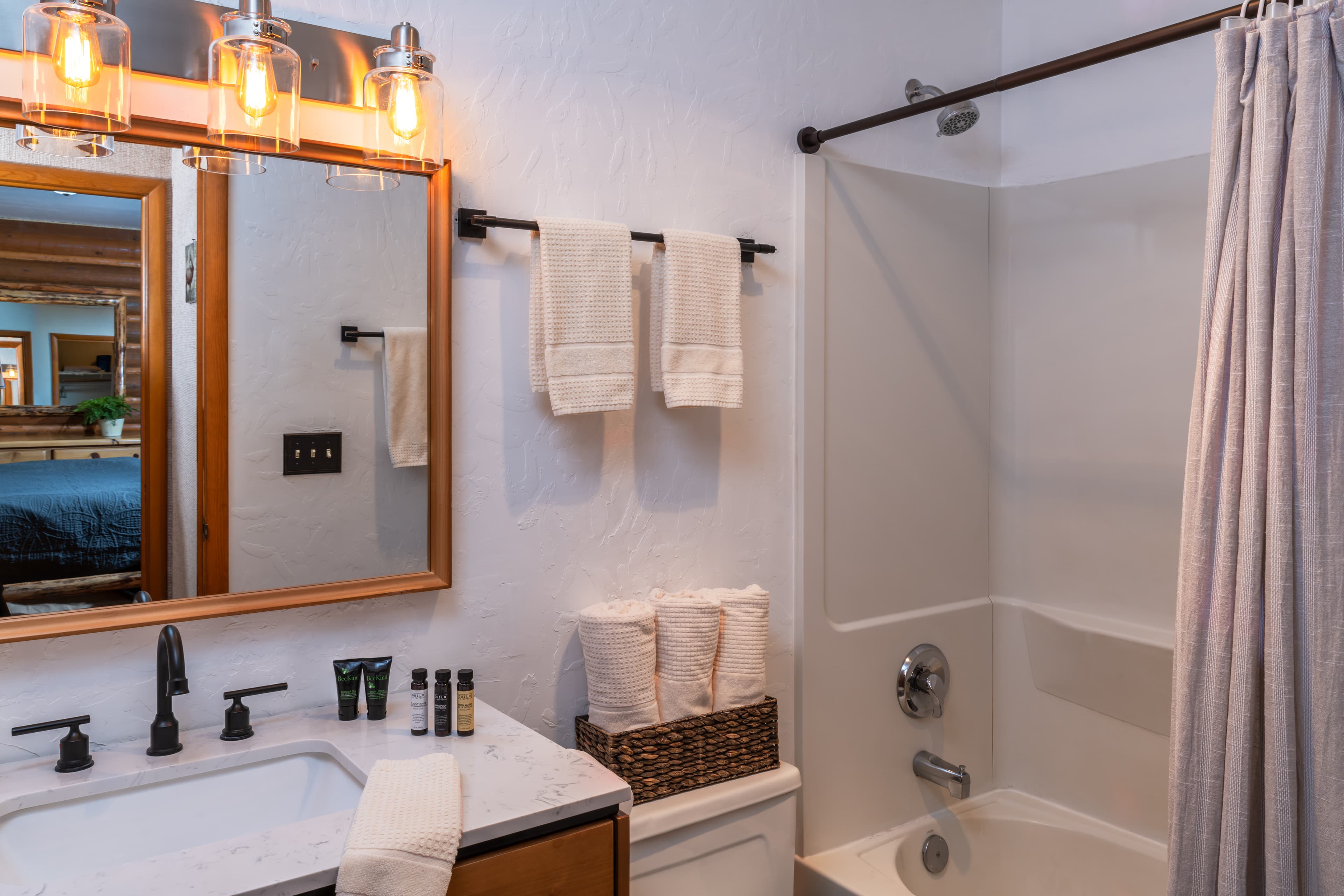 A modern bathroom featuring a mirror, sink, shower, and neatly arranged towels.