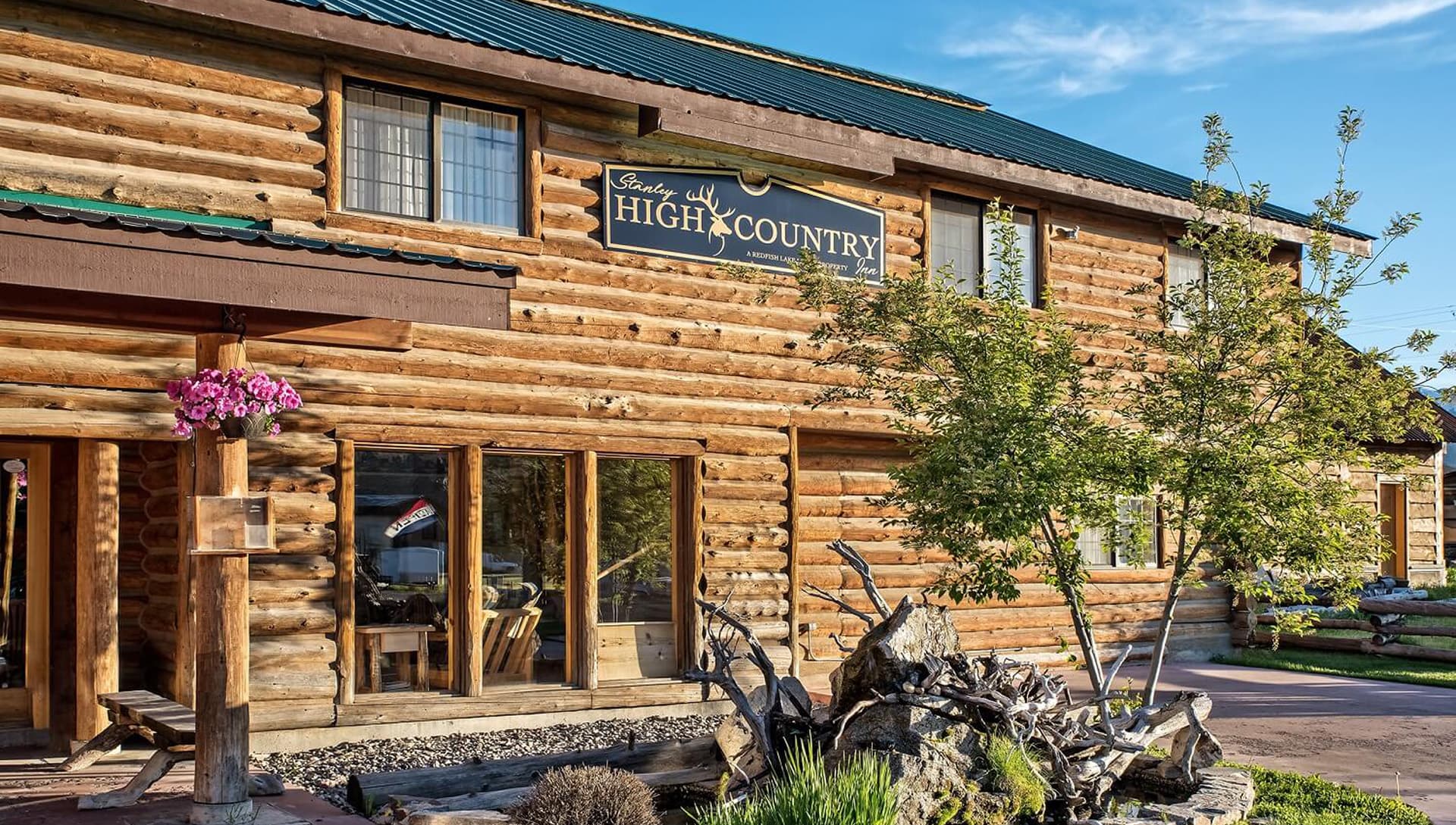 Log cabin building with a sign reading "High Country" and landscaped entrance.